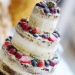 How to Decorate a Wedding Cake Table How to decorate a wedding cake table: elegant floral arrangements, cascading fabric, and ornate cake stand